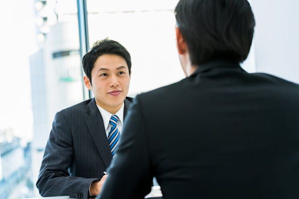 向かい合って座っているスーツを着た男性