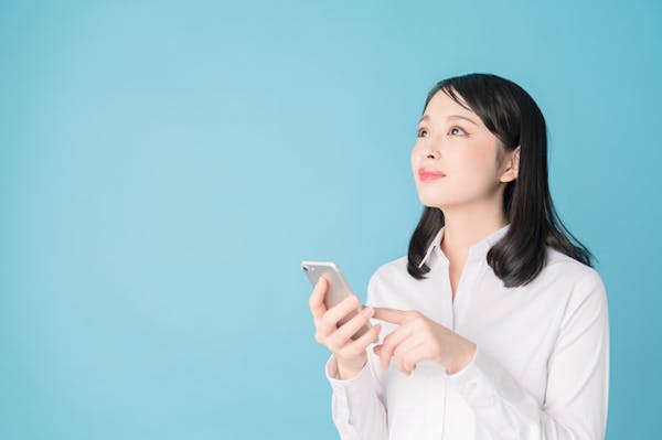 スマホでエアコンを操作する女性