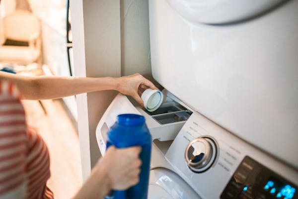 洗濯機に洗剤を入れる女性