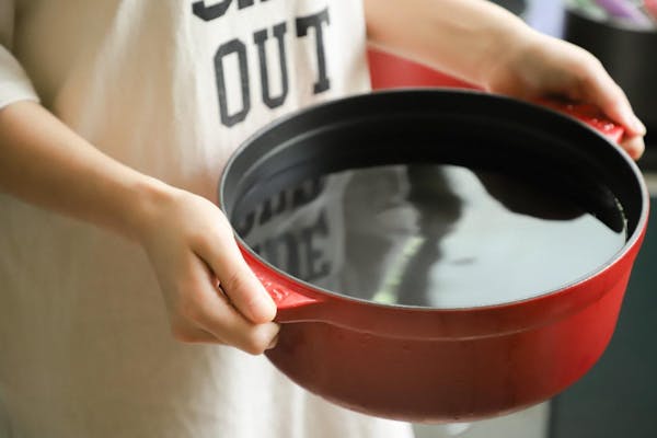 水の入った鍋を持つ女性