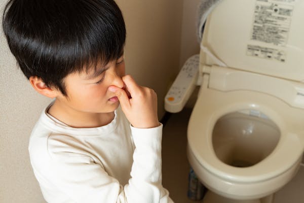 トイレの臭いに鼻をつまむ子ども