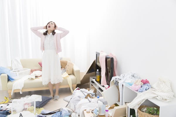 散らかった部屋に悩む女性