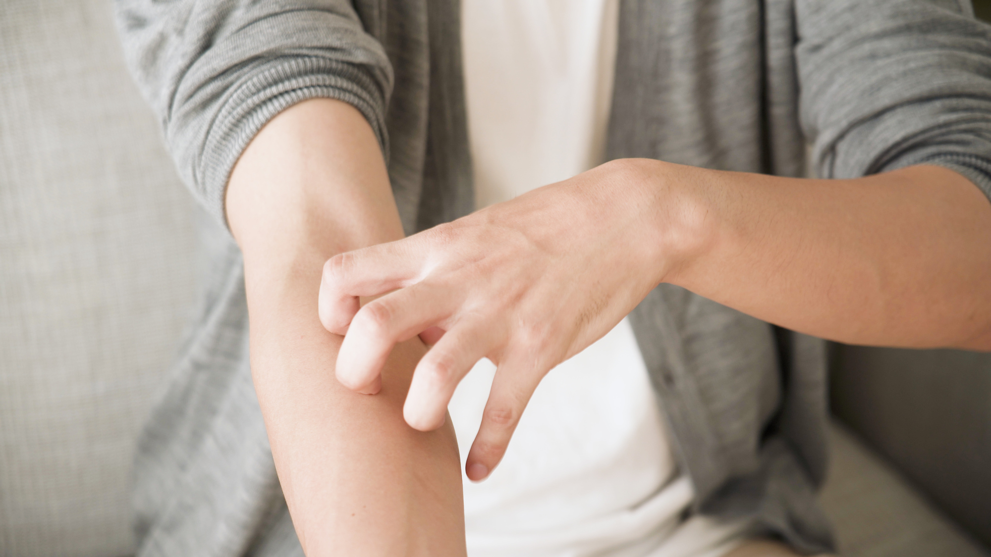 腕をかきむしる男性